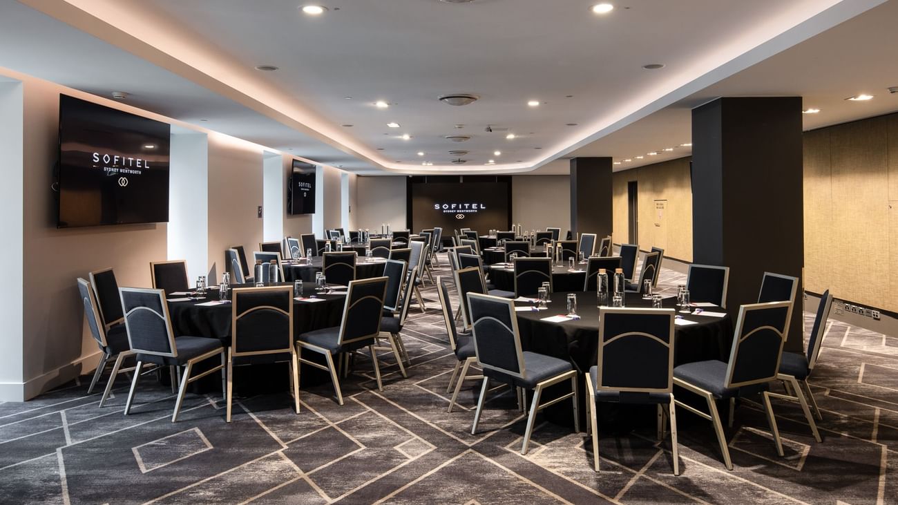 Adelaide room meeting space with round tables, black chairs and modern conference setup