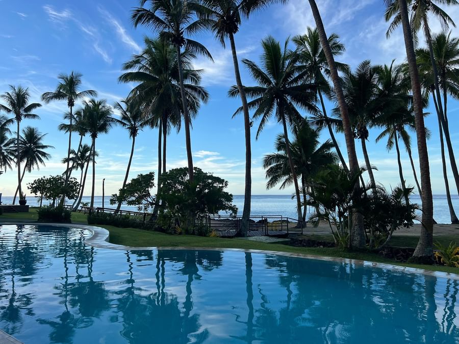 Resort pool with palm trees and ocean view at Tambua Sands Beach Resort - Fiji.