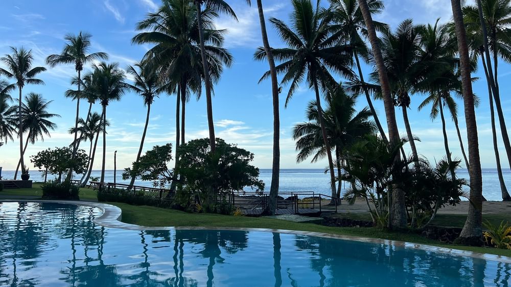 Clear pool with palm trees and ocean view at Tambua Sands Beach Resort in Sigatoka.