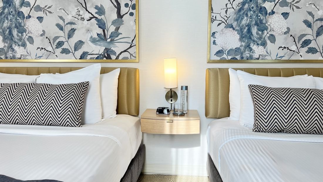 Two queen beds with white linens and patterned pillows at Warwick Allerton Chicago
