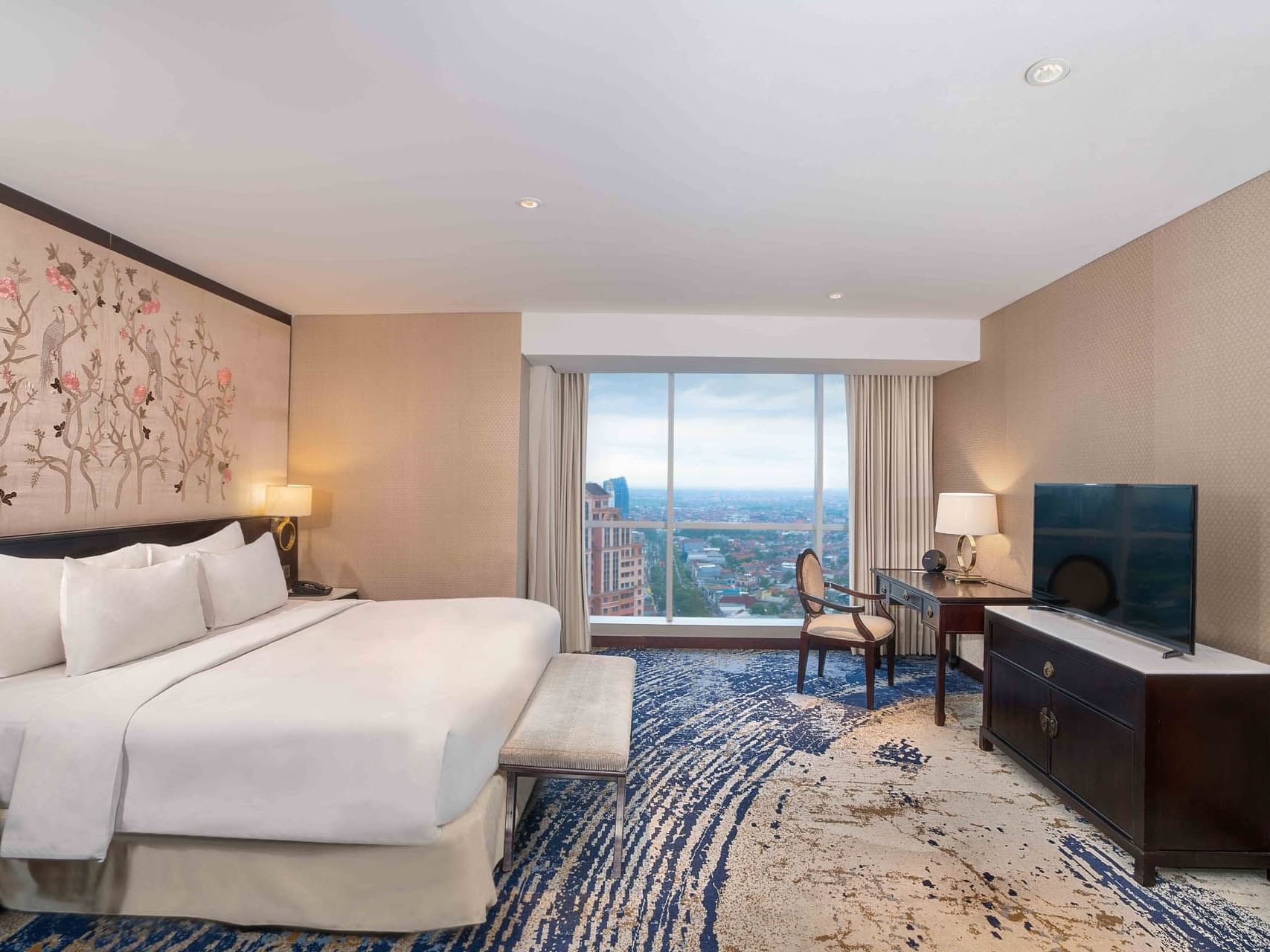 TV-facing bed with workspace and city view in Breccia Room at Vasa Hotel Surabaya