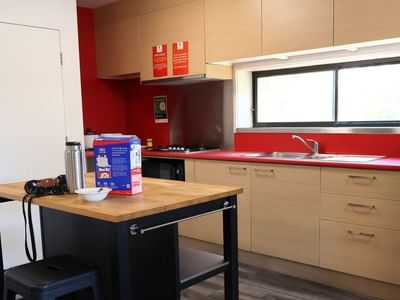 Modern kitchen with red counters, wooden cabinets, and appliances at La Trobe University Hillside Apartments.