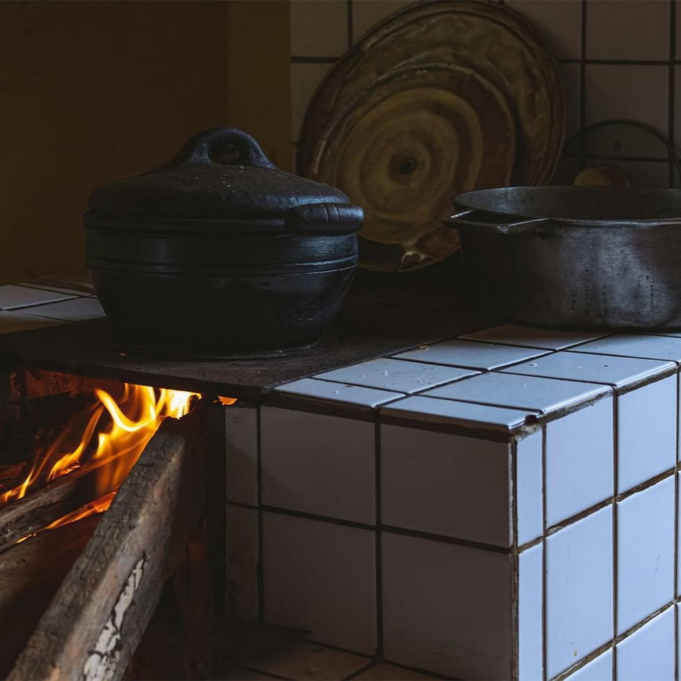 Cooking pots on a hot plate with a burning wood fire underneath for Miasl Cooking Workshop.
