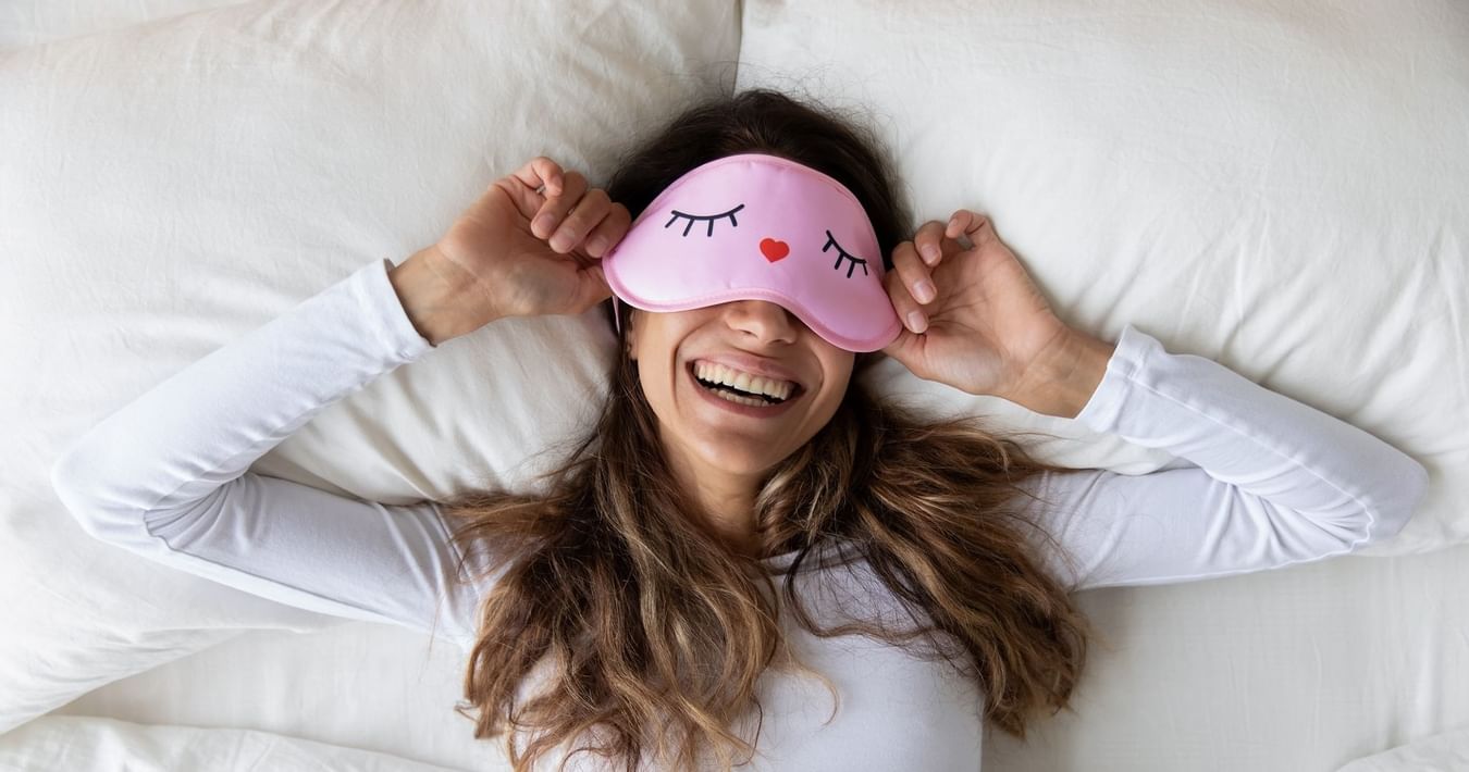Lady relaxing on a bed with a sleep mask, The Originals Hotels