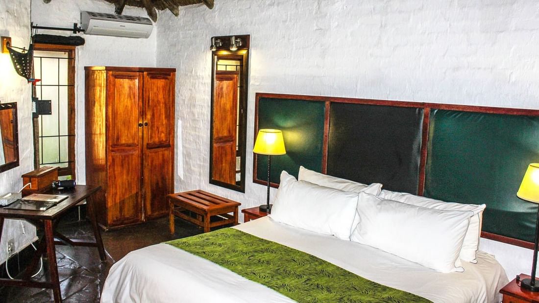 King-size bed with wooden closet in Super Deluxe Room at Kedar Heritage Lodge, Conference Centre & Spa