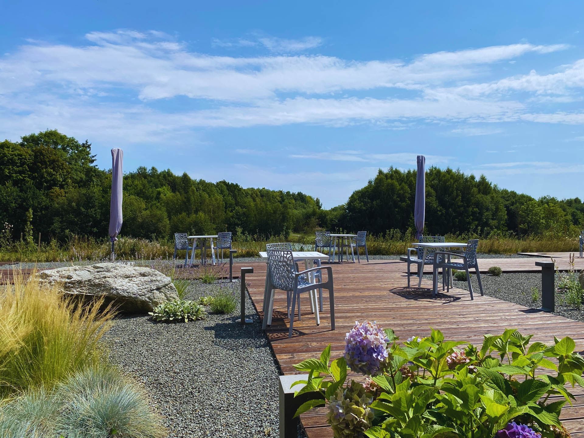 Scenic outdoor patio with modern furniture, surrounded by greenery and colorful flowers at the Avaneo Hotel Marktredwitz
