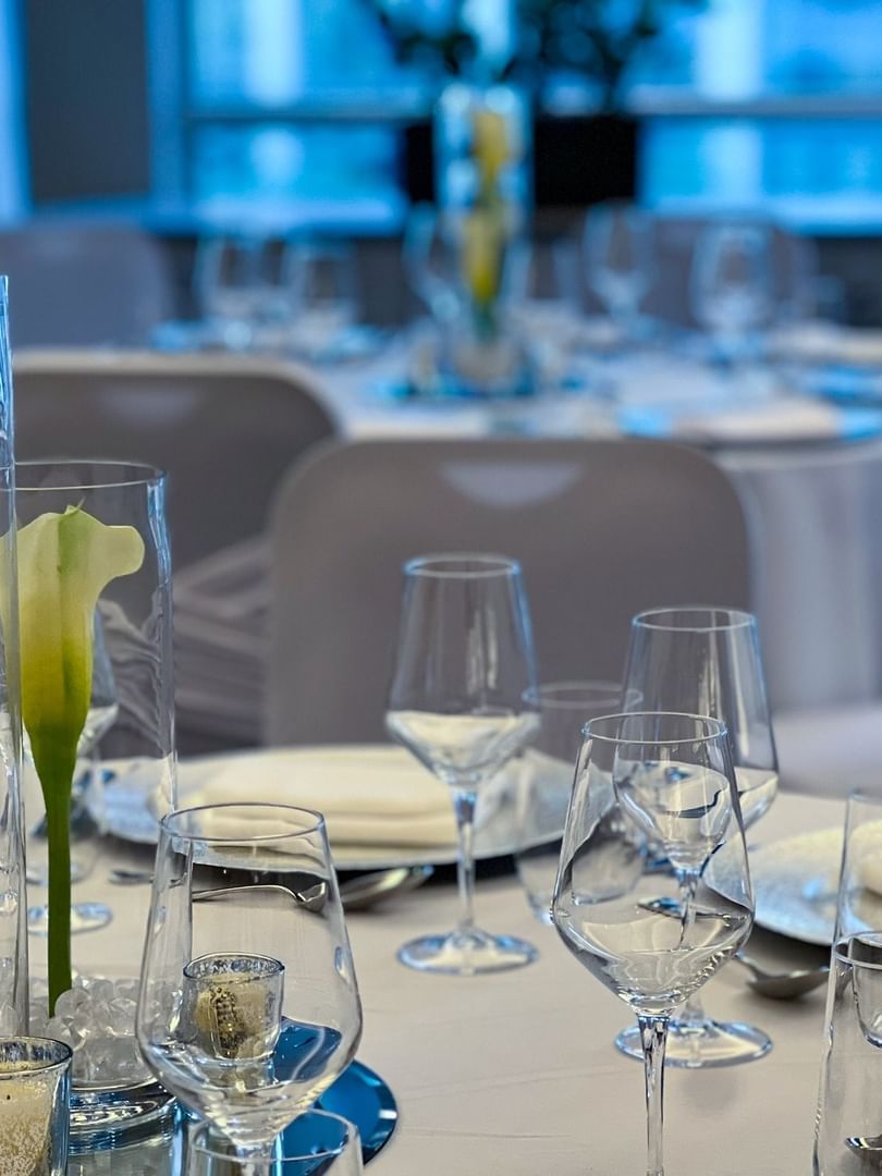 Tall glass vases with calla lilies on mirrored centerpieces by crystal glasses in Ballroom at Warwick Le Crystal Montreal