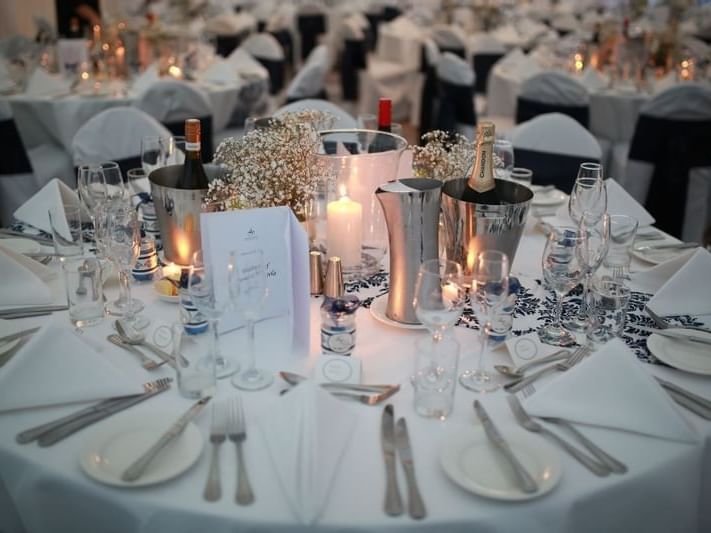Wedding table set with silverware, wine bottles, and candles in the Bridge & Yarra Room at Amora Herencia Riverwalk