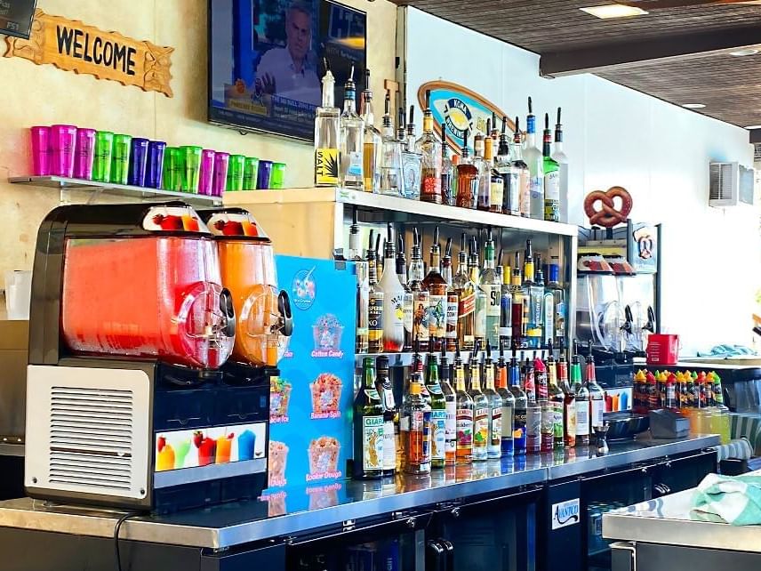 a bar with many bottles of alcohol and two slushy machines