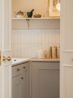 Studio Apartment kitchenette with white cabinetry, brass fixtures, and warm lighting at The Capital Hotel, Apartments & Townhouse.