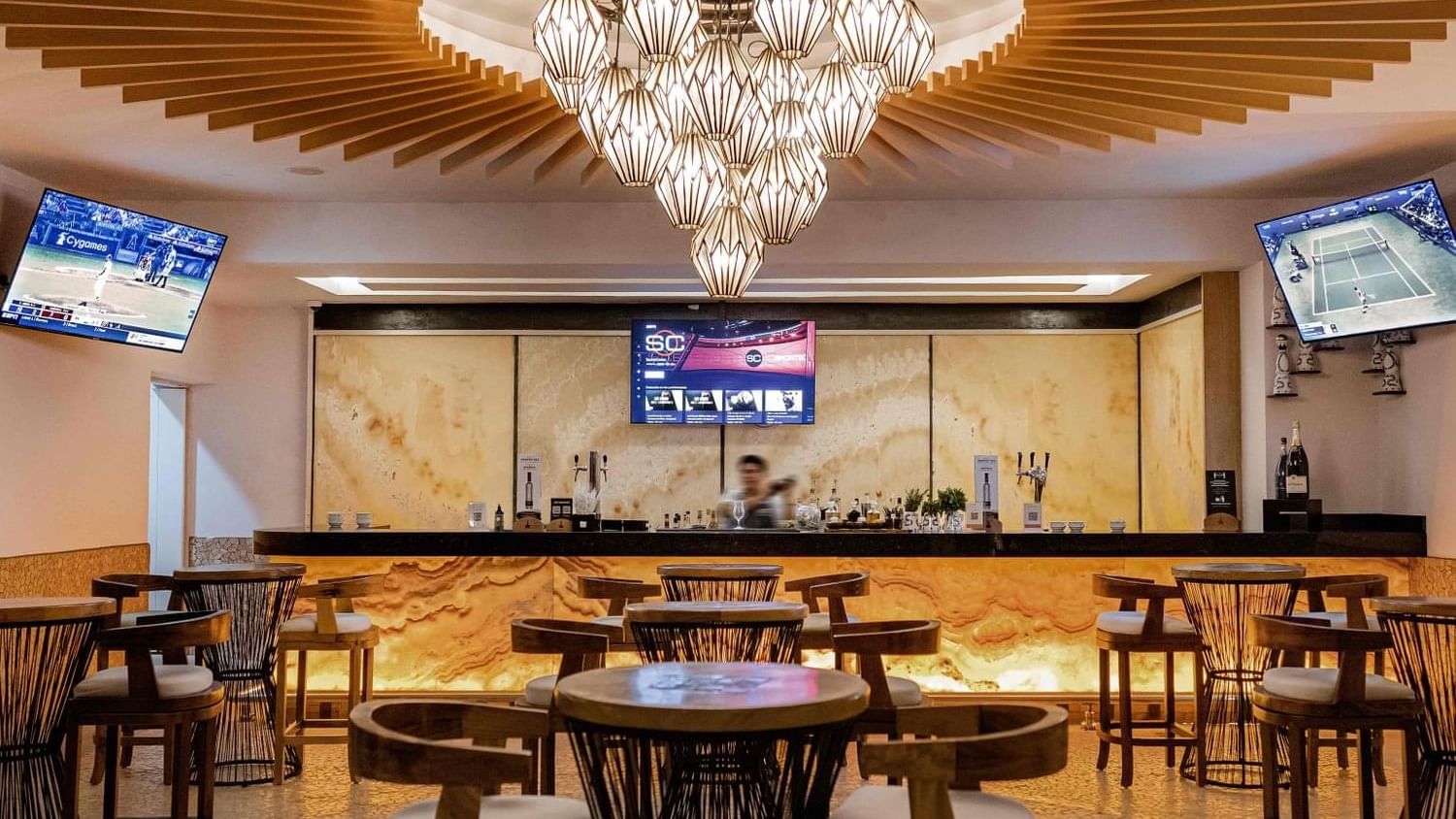 Interior de Suspiro Bar con mesas, sillas y televisores en Marquis Los Cabos Resort & Spa en San José del Cabo.