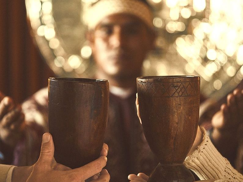 Two people holding two cups closely that's made of wood