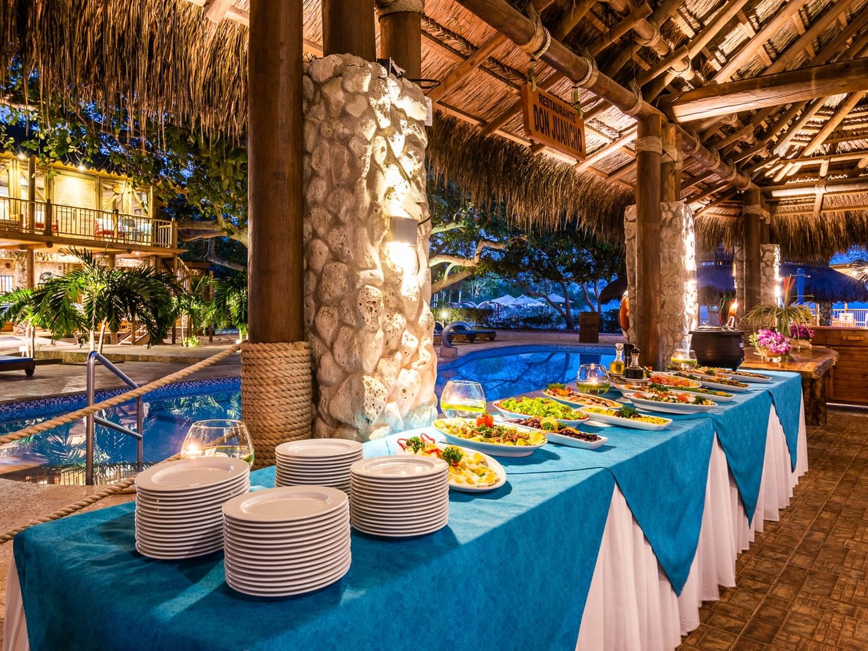 Food arranged with plates in buffet area by pool at Hotel Isla Del Encanto