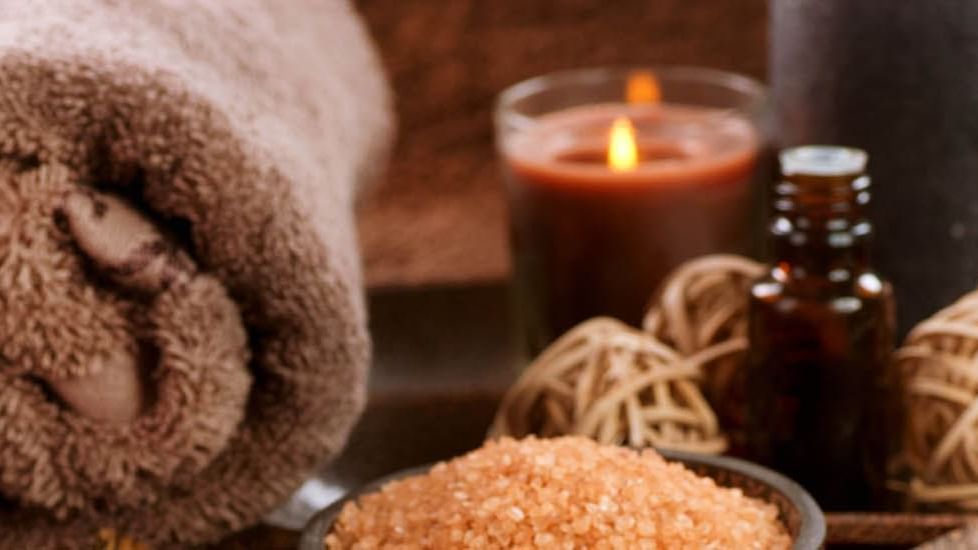 Serviettes et bougies de massage sur une table avec des sels de bain et des décorations.