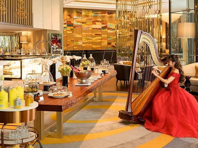  A woman in a red dress plays a harp, adding a touch of elegance to the hotel lobby