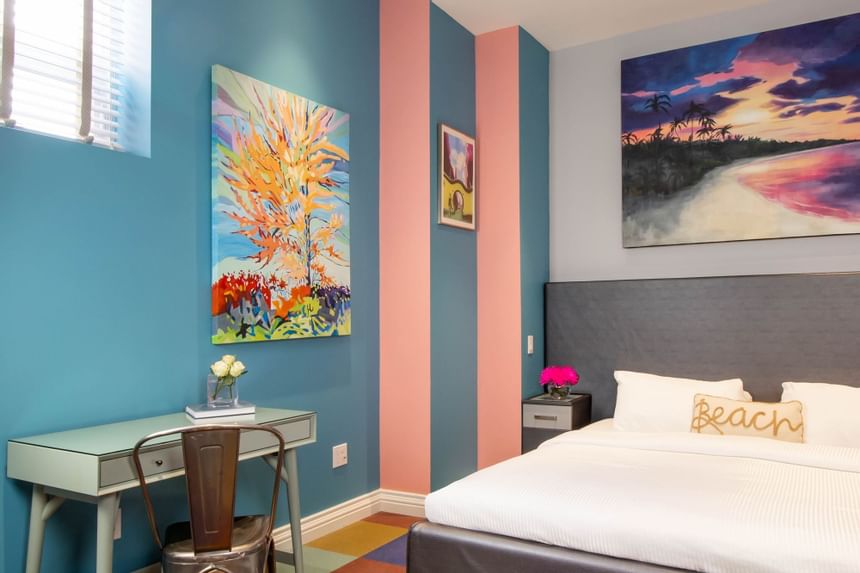 King Superior South Beach interior with work desk, paintings on the wall & fresh flowers in vases at Retro Suites Hotel