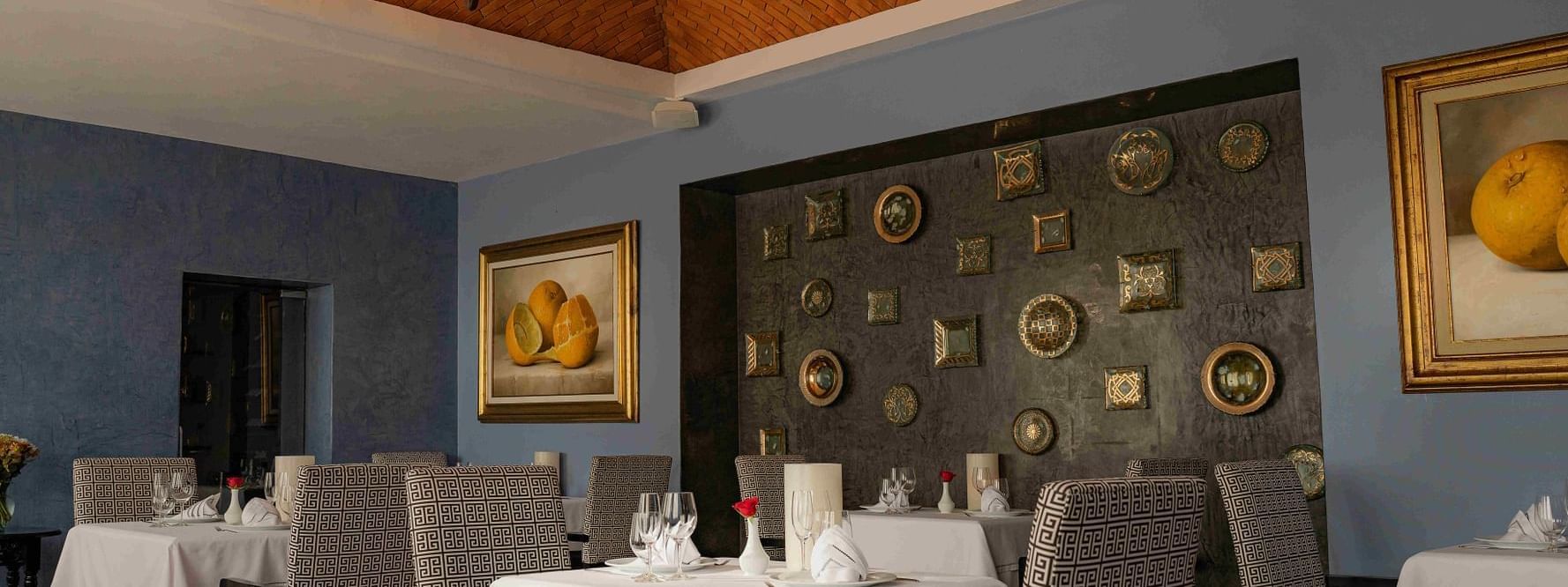 Elegant dining room with white tablecloths, unique chandelier, and art, at the Marquis Los Cabos Resort