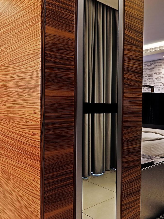 Polished wood wardrobe by a plush rug and television under soft lighting in Junior Suite at Warwick Stone 55 - Beirut