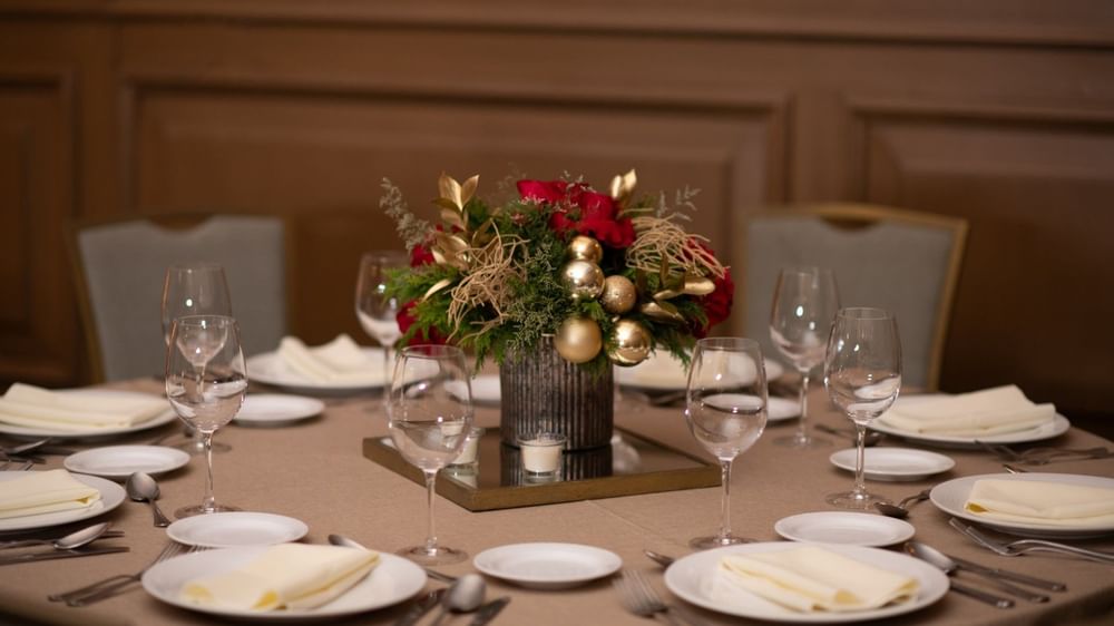 Dinner table in Salon Duque with a floral centerpiece, gold ornaments, and elegant glassware at Quinta Real Monterrey