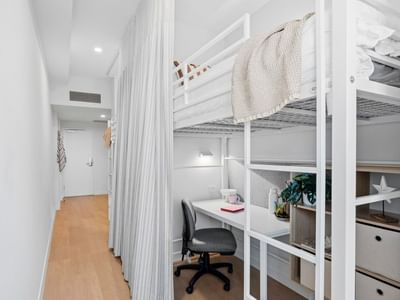 Bunk bed, desk, and curtained privacy area in a hotel room at UniLodge Brisbane City.