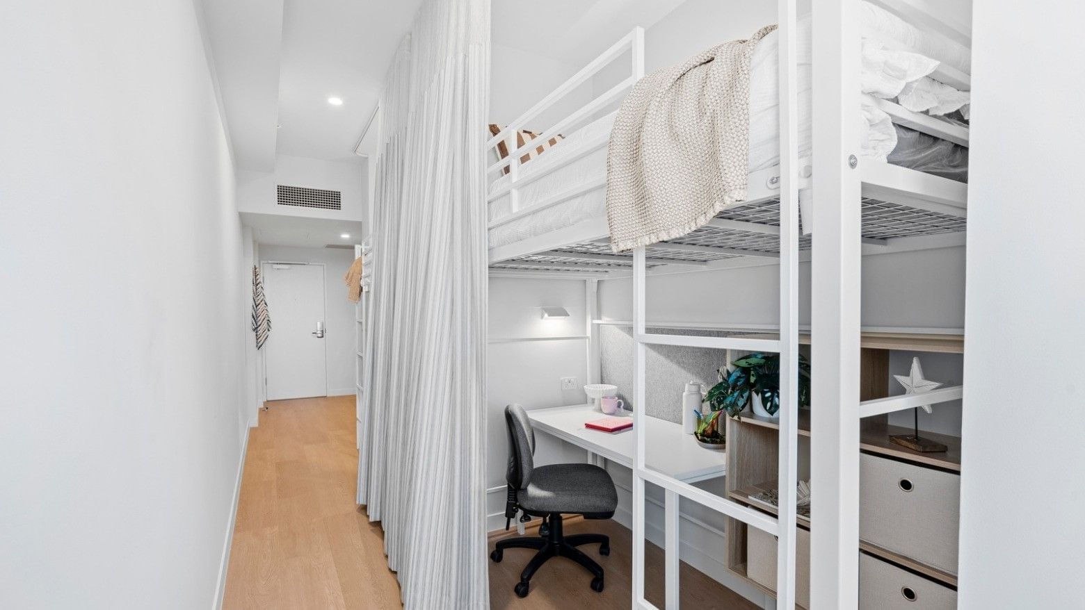 Bunk bed, desk, and curtained privacy area in a hotel room at UniLodge Brisbane City.
