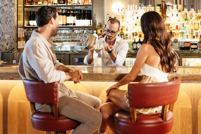 Bartender shaking a cocktail by guests seated at the bar at Elysium Hotels, the best hotels in Neutral Bay, Sydney