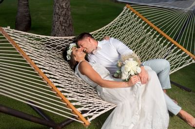 A married couple posing on a hammock at Bougainvillea Barbados