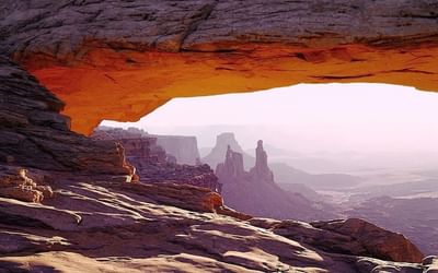 Stunning view through Mesa Arch in Canyonlands, with towering rock formations and distant mountains near Moab Valley Inn