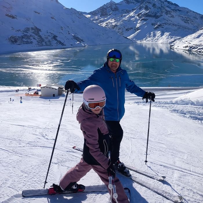 Vater und Tochter auf Skiern vor einem See im Schnee bei Falkensteiner Hotel Montafon