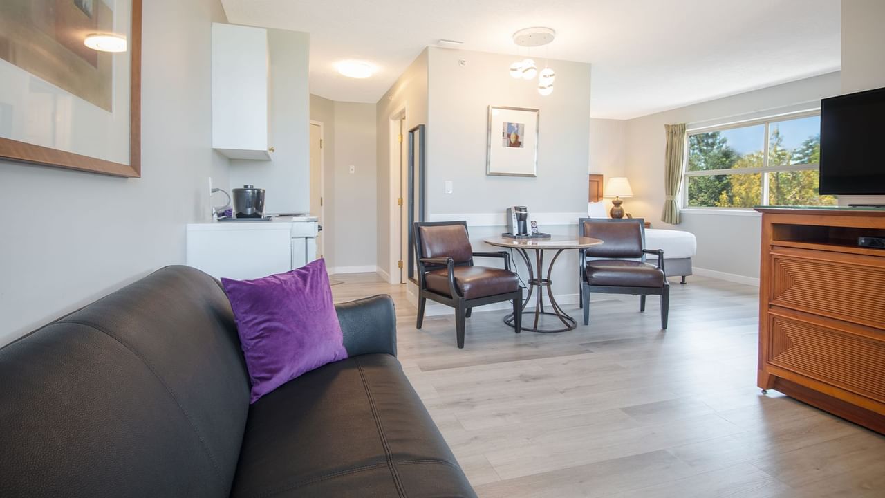 Hotel suite with queen bed, couch, flat screen TV, table and chairs