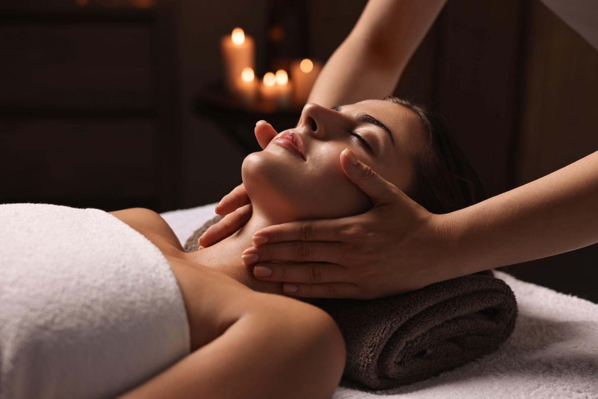 A soothing close-up of a woman receiving a relaxing massage at The Londoner Hotel spa with soft, warm lighting