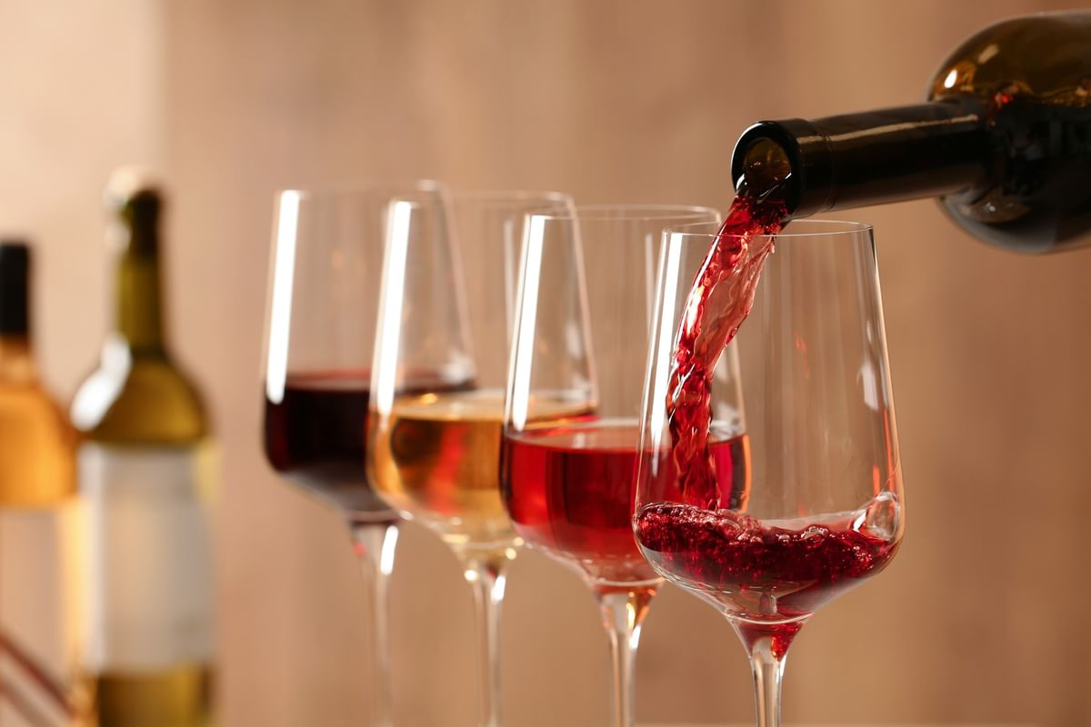 Vin rouge versé dans un verre avec d'autres verres de vin en arrière-plan au Warwick Reine Astrid-Lyon