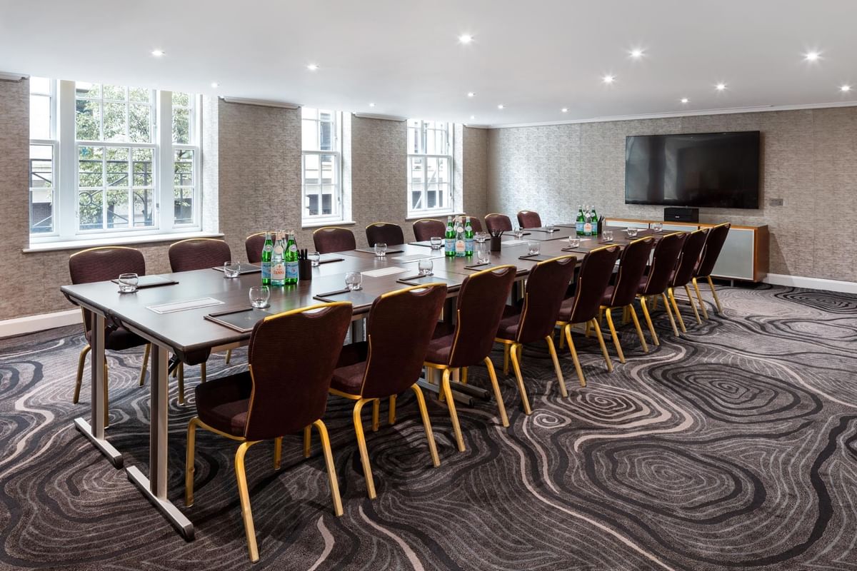 Boardroom set-up with TV in a meeting room with carpeted floors at May Fair Hotel