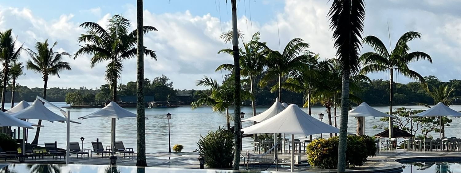 Palm trees and beach umbrellas near swimming pool at Warwick Le Lagon - Vanuatu, Efate