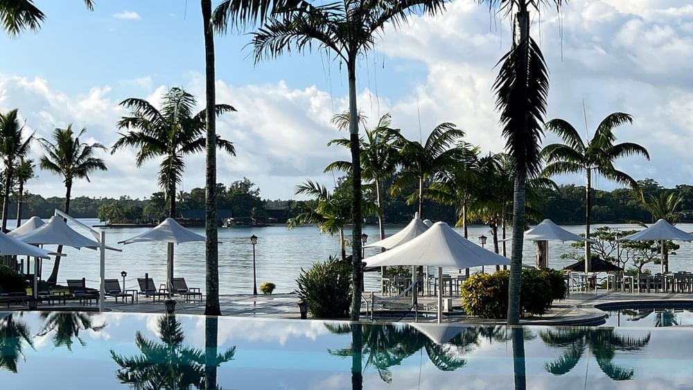 Palm trees and beach umbrellas near swimming pool at Warwick Le Lagon - Vanuatu, Efate.