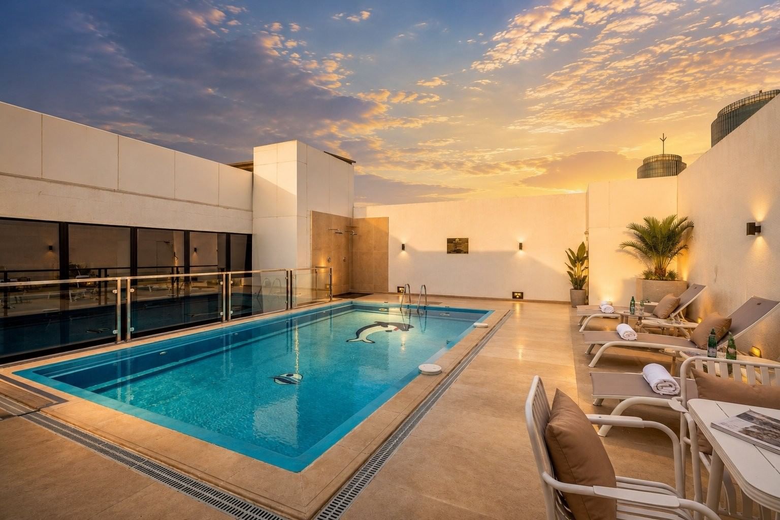 Rooftop pool under sunset sky with water beside lounge chairs at Naviti by Warwick Jeddah, featuring a peaceful boutique stay