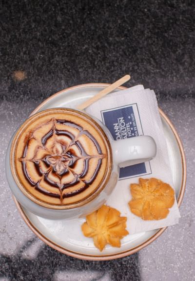 Beautifully crafted coffee, accompanied by cookies and a napkin in Cafe Farallones at Dann Carlton Cali