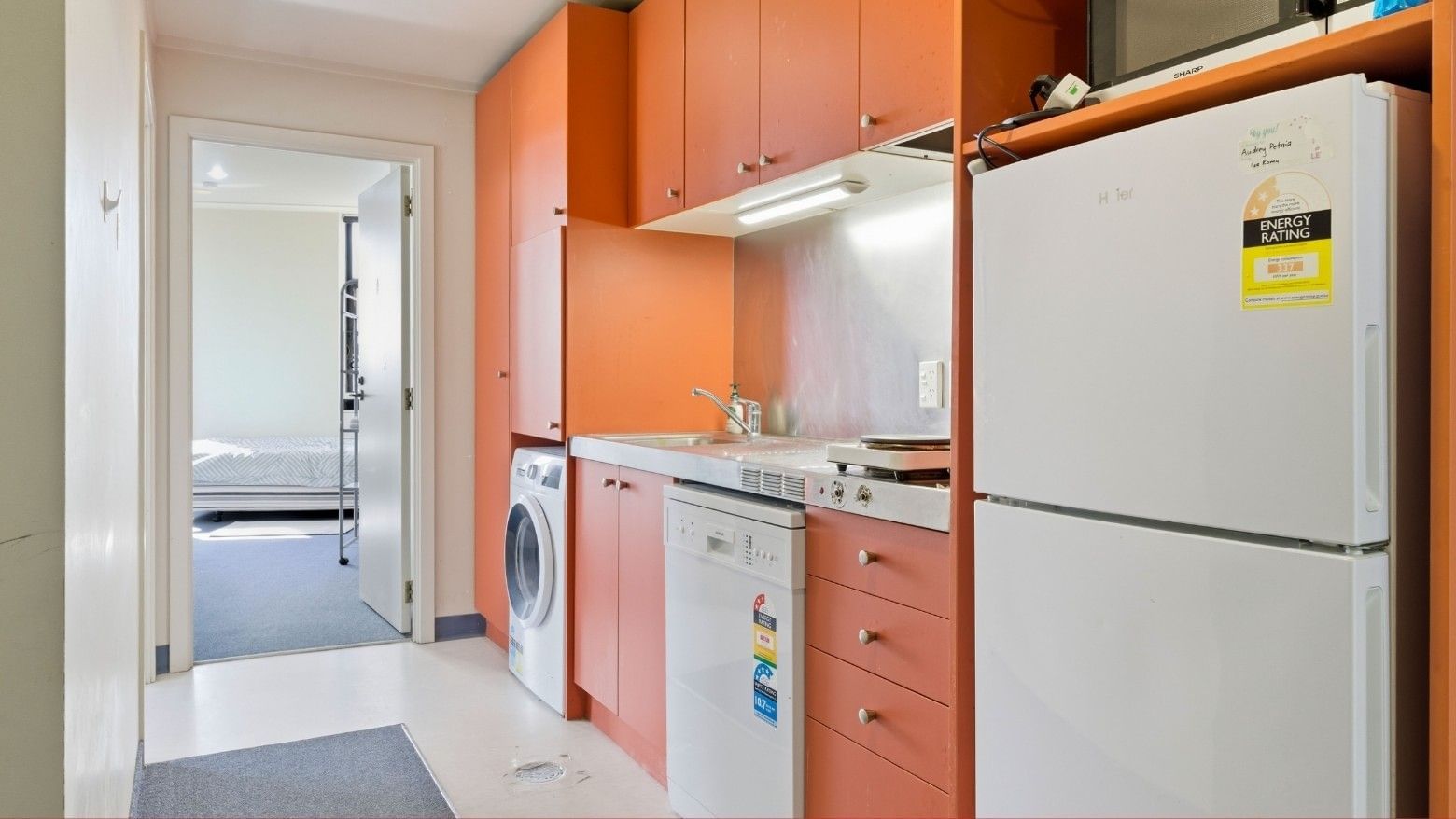 Modern kitchen with orange cabinets, white appliances, and a hallway view at UniLodge Stafford House.