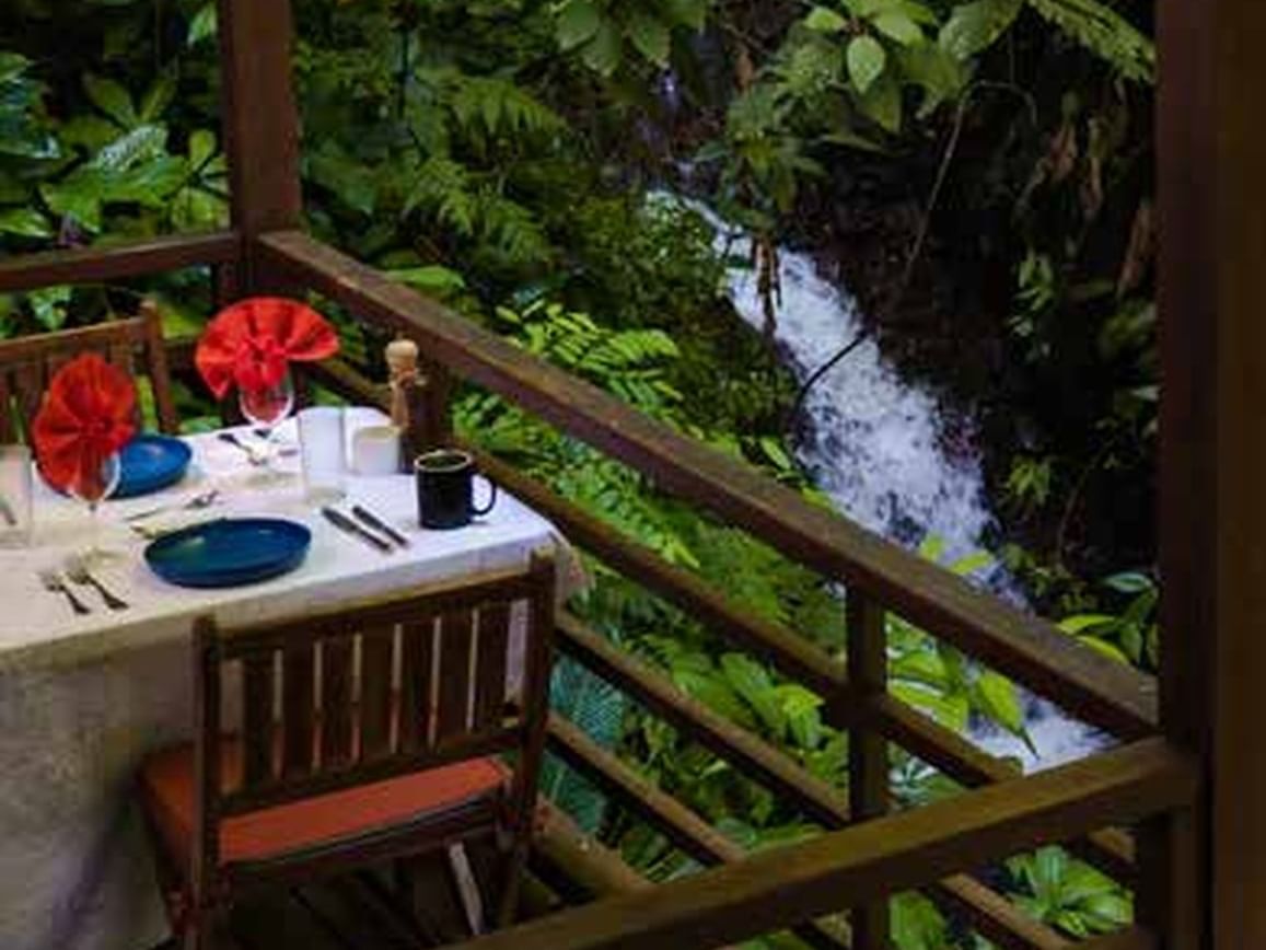 Mesa de comedor arreglada cerca de la cascada en Playa Cativo Lodge