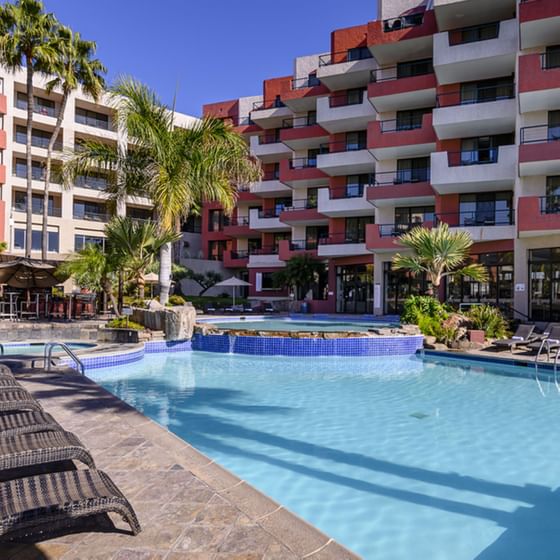 Sunbeds by the outdoor swimming pool at Hotel Coral y Marina