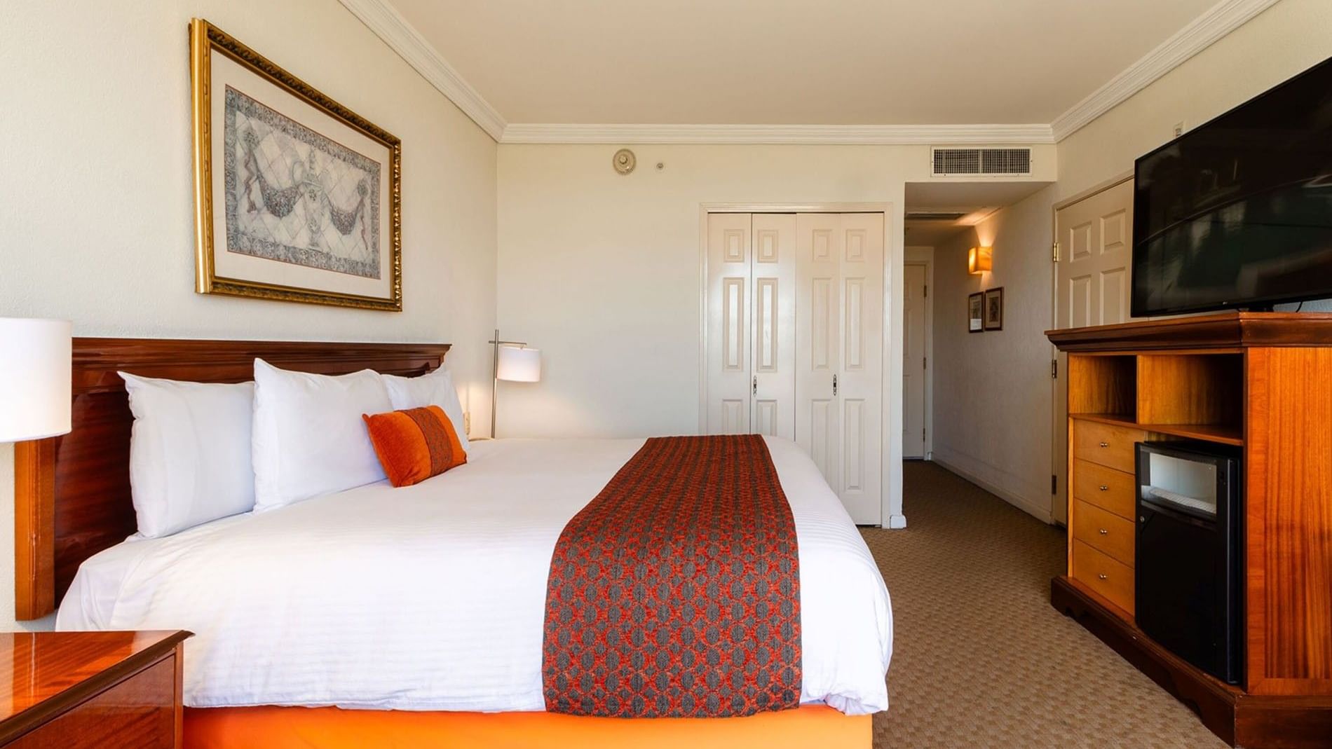 Spacious King Deluxe room with a wooden media console and a well-lit hallway area at Camino Real Puebla Angelopolis