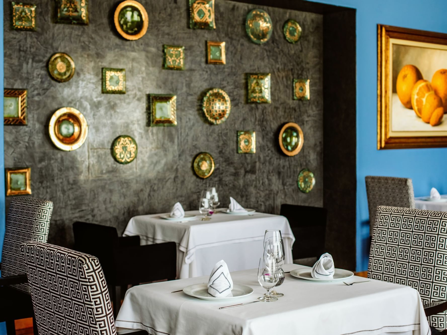 Dining tables by a wall with antique wall plates in Los Cabos