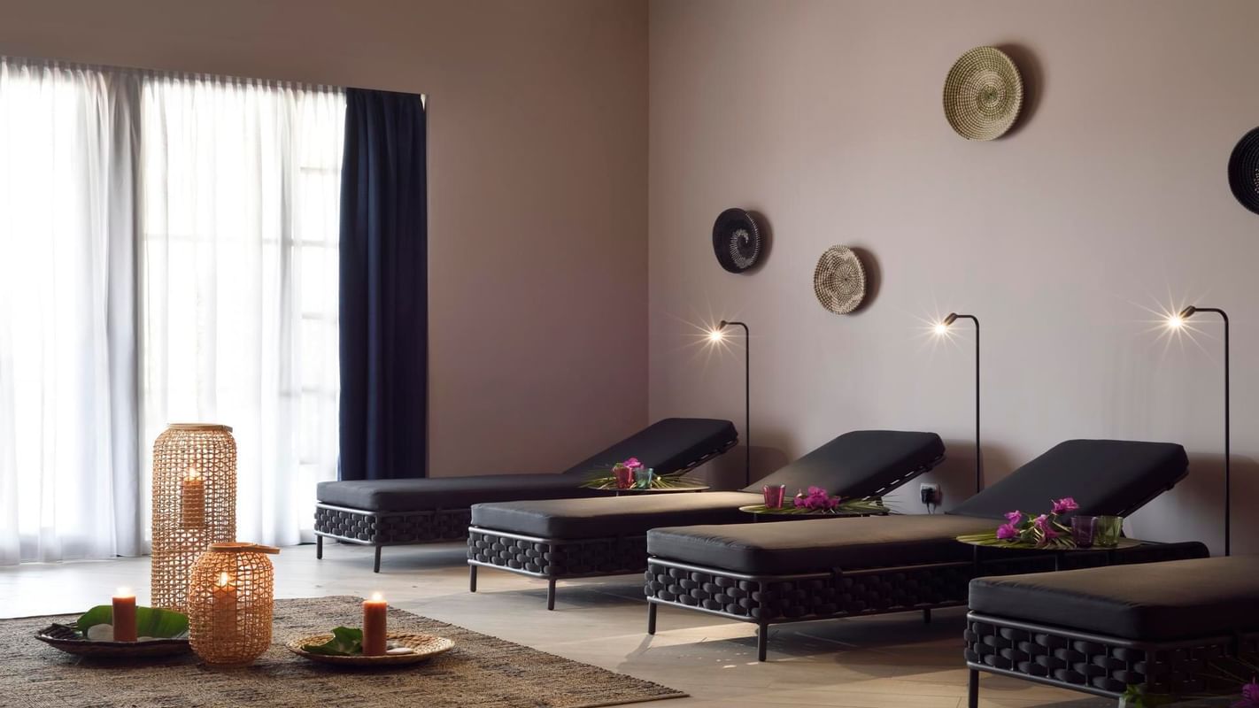 Serie di lettini da massaggio in una sala relax con decorazioni, candele e luci soffuse.