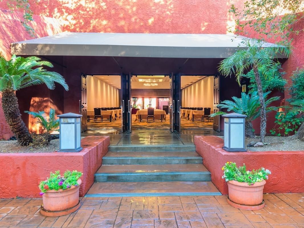 Outdoor event space entrance with terracotta walls, palm trees, and illuminated interior at Hilton Phoenix at the Peak