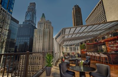 Upstairs at The Kimberly bar counter and black chairs facing city high-rises in lounge terrace in The Kimberly Hotel