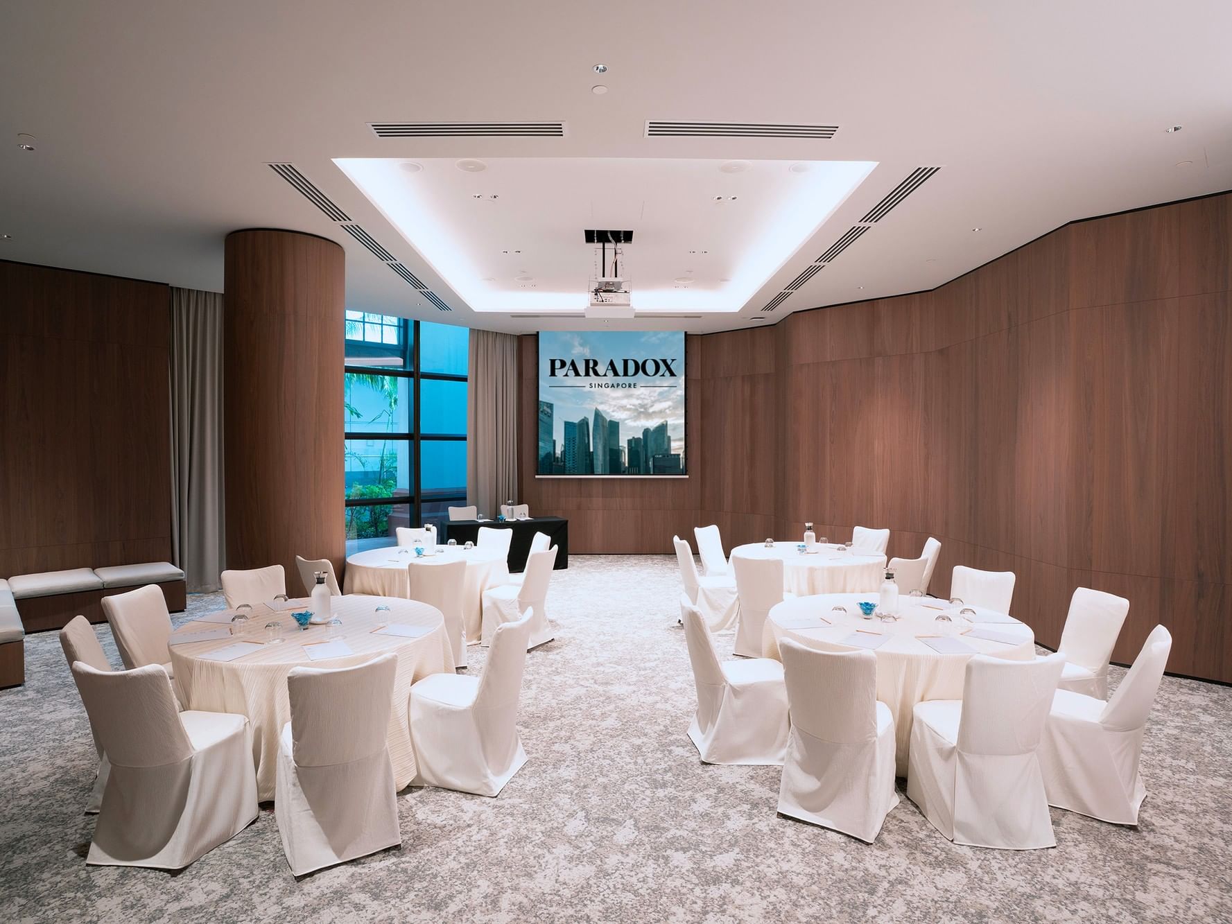 Cluster-style meeting room setup in the Sandalwood at Paradox Singapore, featuring neatly arranged tables, chairs, and professional conference amenities.