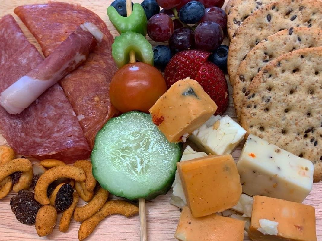 Wooden tray with cheese, crackers, fruit, and meat served on a table at Temple Gardens Hotel & Spa