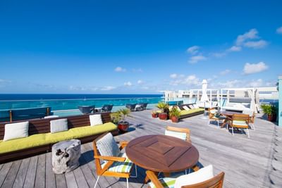 Rooftop terrace with stylish seating, surrounded by lush plants, overlooking the ocean at The Residences at Seafire