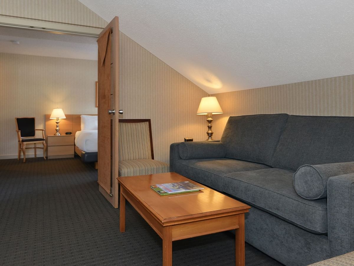 Spacious hotel suite with a king bed, elegant decor, and sofa bed.