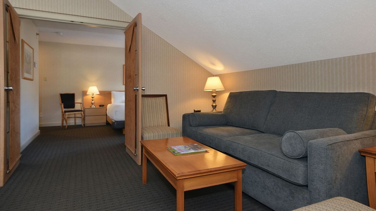 Spacious hotel suite with a king bed, elegant decor, and sofa bed.